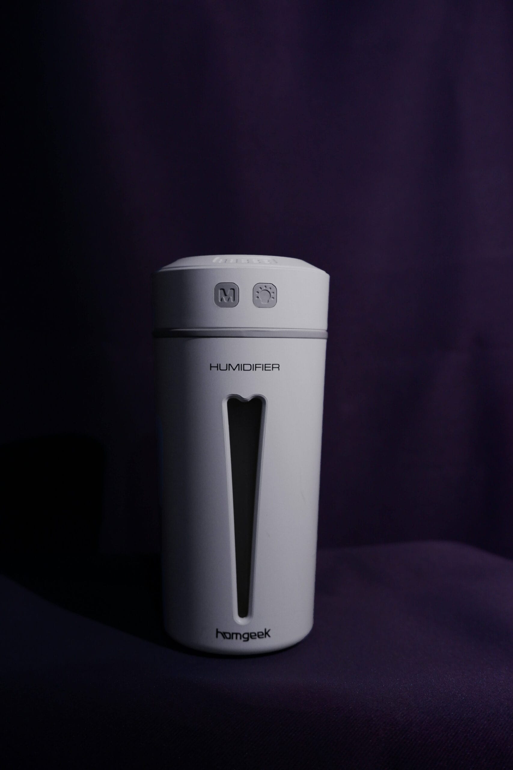 White air purifier running quietly next to a bed