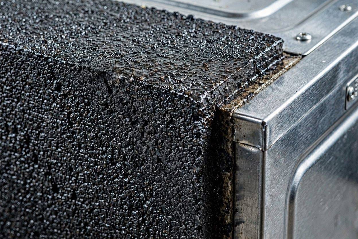 A close-up of the heavy acoustic insulation and sound dampening material on the outside of a premium dishwasher tub