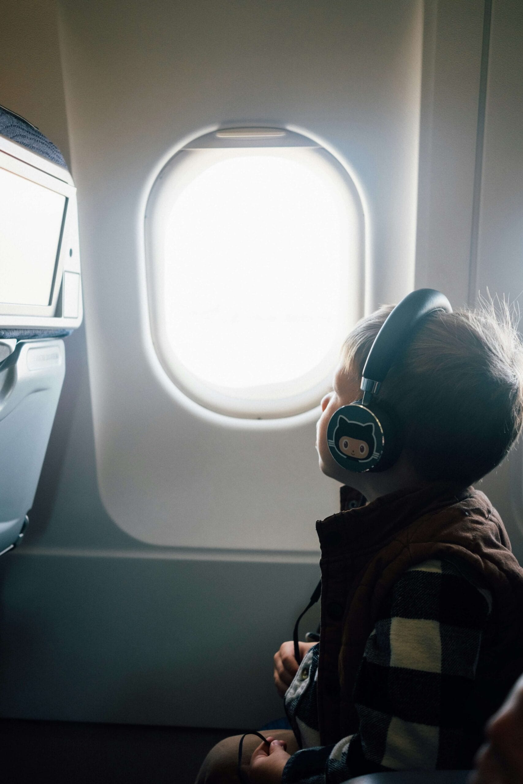 Child wearing safe volume-limited noise canceling headphones on an airplane